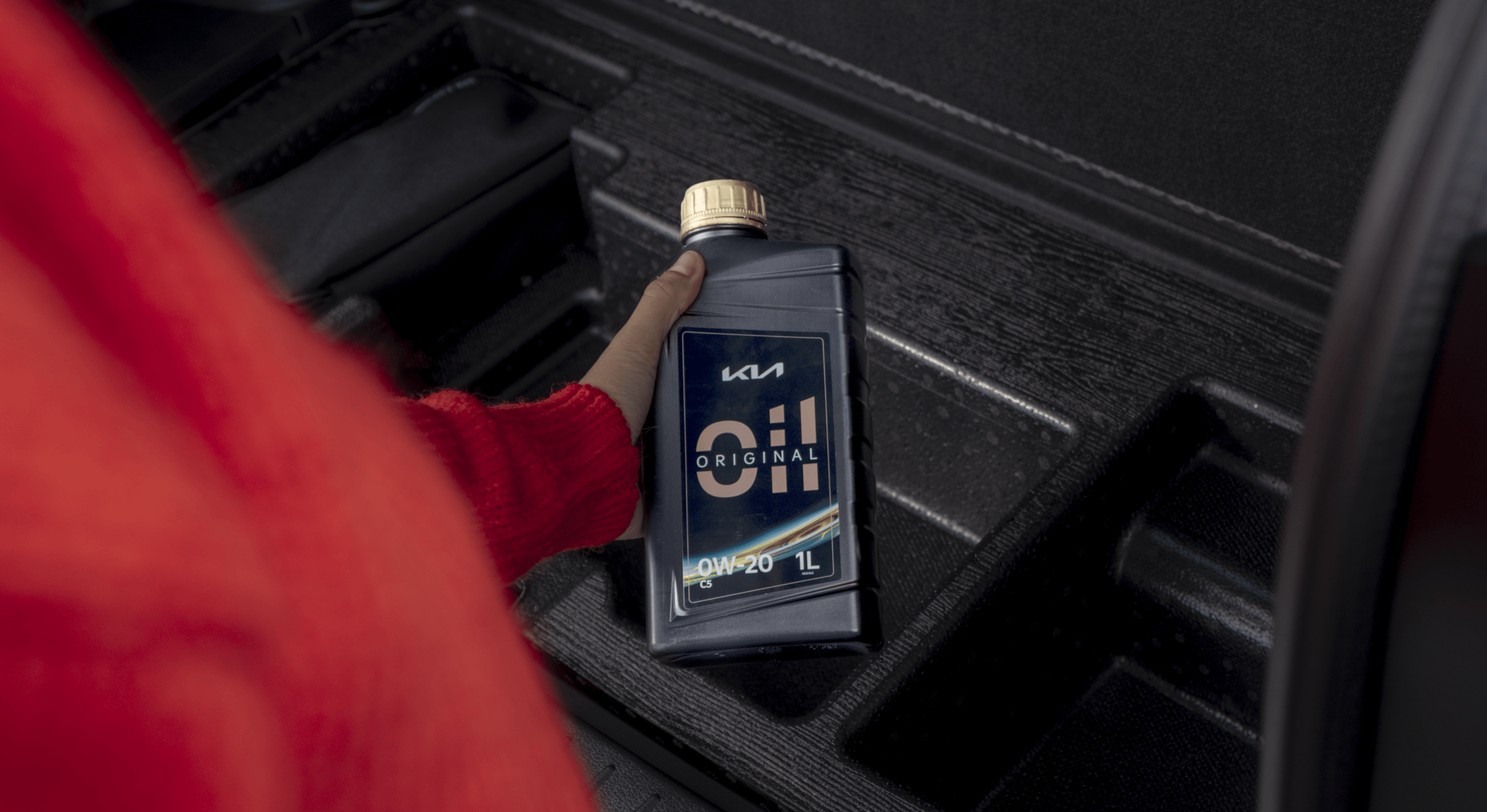 Ein Kia Kunde hält eine Flasche Kia Originalöl in der Hand.